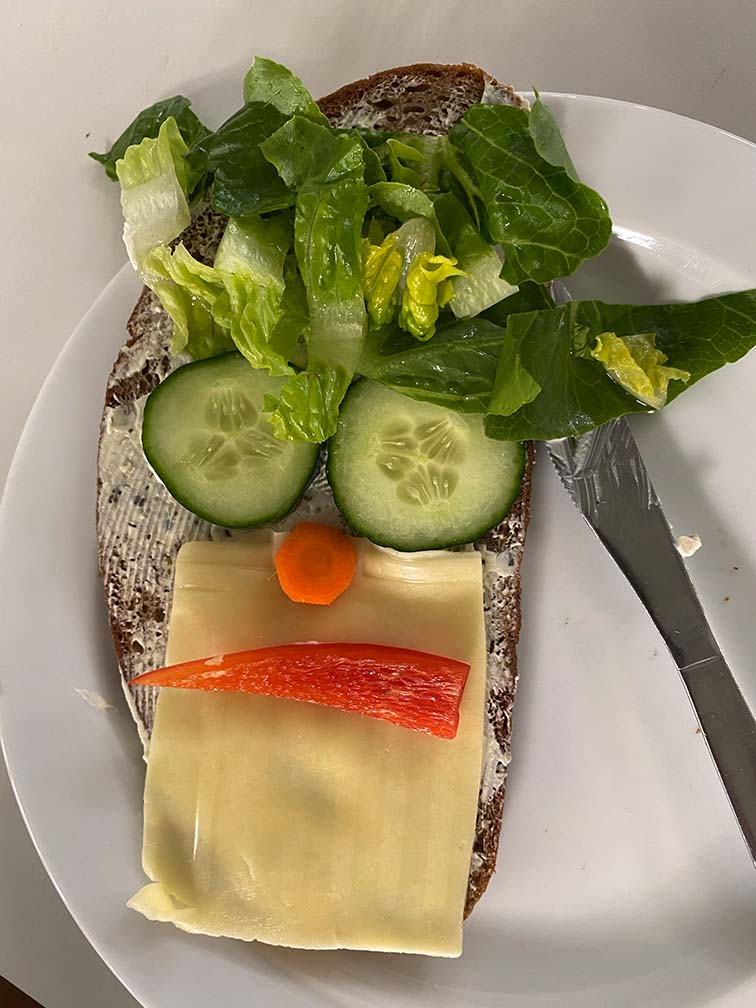 Ein Brot was mit Gemüse belegt ist und ein Gesicht ergibt